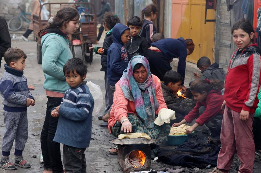 A displaced Palestinian woman cooks bread over a fire in Rafah Sunday.