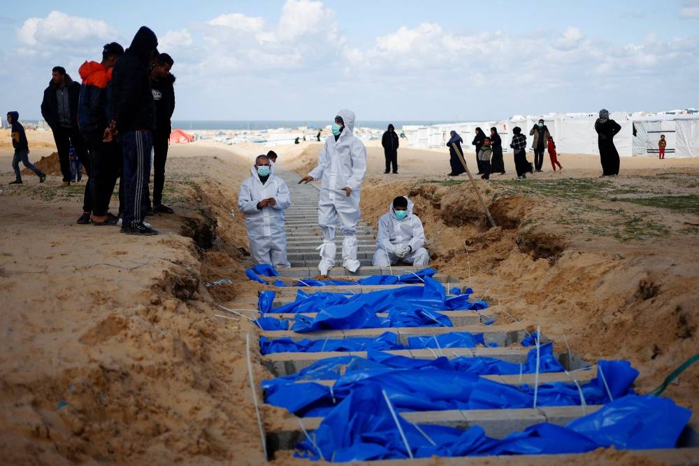 People bury Palestinians, including those who were killed in Israeli strikes and fire, after their bodies were released by Israel, according to Palestinian health ministry officials at a mass grave in Rafah, in the southern Gaza Strip, on Tuesday. REUTERS
