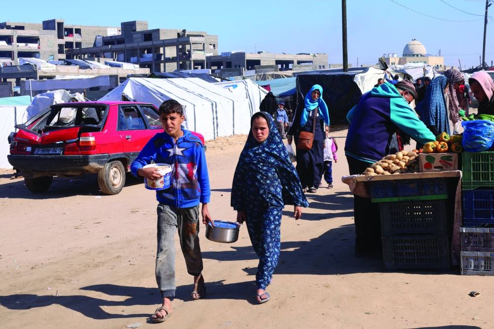 A displaced Palestinian boy carries a cooking pot as he walks with his sister at a tent camp, amid the ongoing conflict, in Rafah, in the southern Gaza Strip, on Wednesday.
