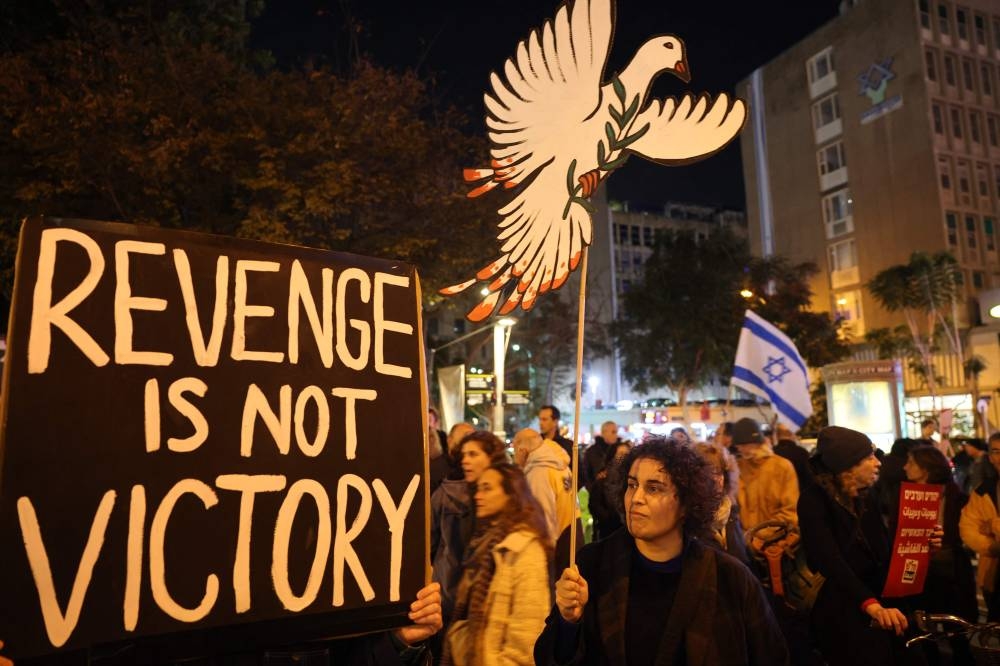 Israeli left wing activists lift placards and banners as they rally against the war in Gaza outside the Ministry of Defence in Tel Aviv on Saturday. AFP