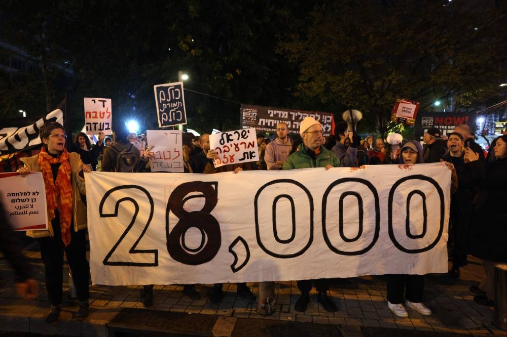 Israeli left wing activists lift placards and banners as they rally against the war in Gaza outside the Ministry of Defence in Tel Avivv on Saturday. AFP