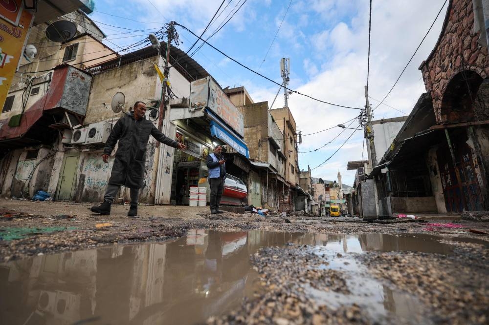 People find their way along a street devastated by the passage of Israeli military vehicles and bulldozers during raids, in the refugee camp of Balata in the occupied West Bank on Sunday. AFP