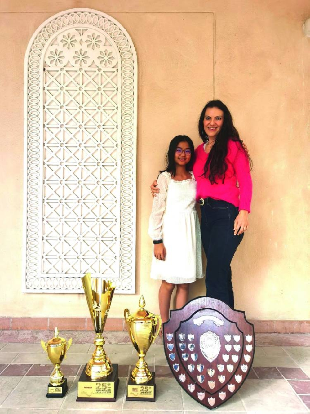 Sze Han Law with violin teacher Lorena Manescu and the prizes she won.