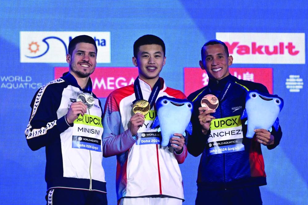 Men’s solo technical artistic swimming gold medallist China’s Yang Shuncheng (centre), silver medallist Italy’s Giorgio Minsini (left) and bronze medallist Colombia’s Gustavo Sanchez pose during the medal ceremony at Aspire Dome in Doha on Monday. (AFP)
