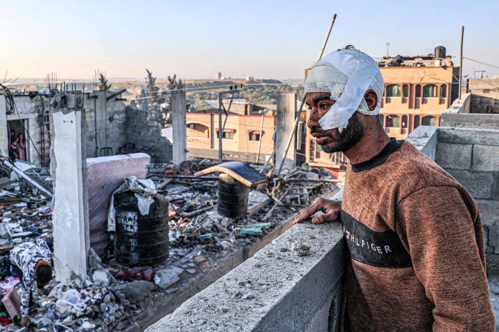 An injured man with a bandaged head looks on while standing next to the rubble and debris of a destroyed building in the aftermath of Israeli bombardment on Rafah in the southern Gaza Strip on Wednesday. AFP