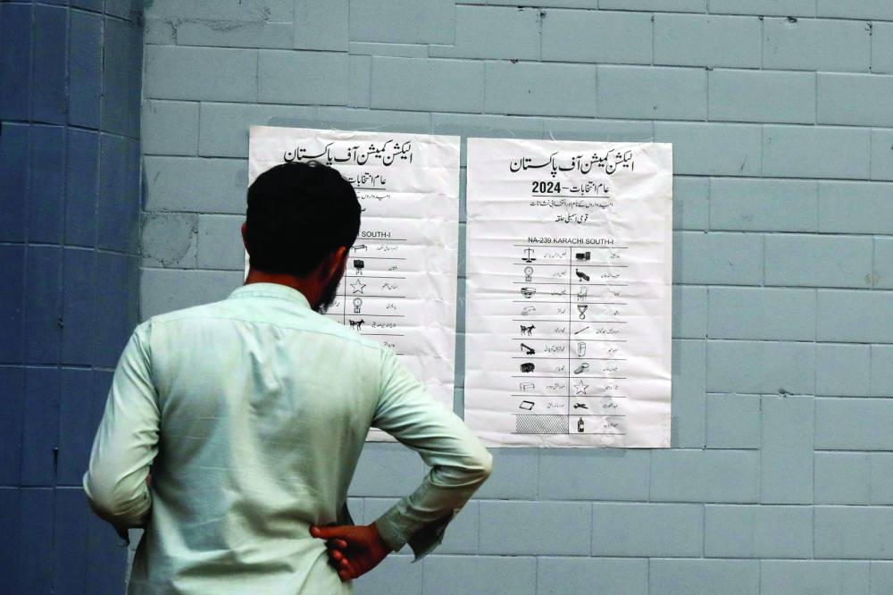 A man looks at a list of contesting candidates and their electoral signs, outside a polling office, set up for general election in Karachi yesterday. (Reuters)