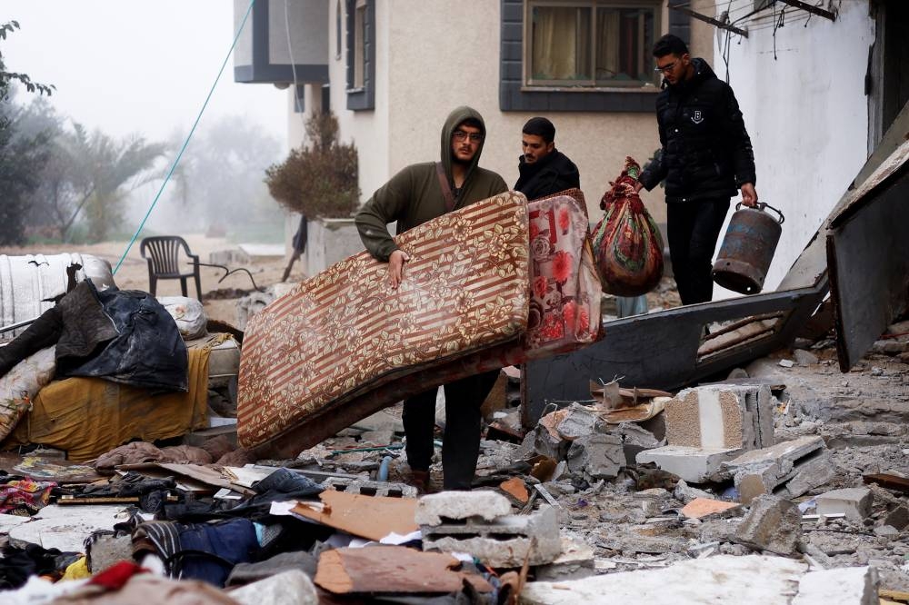 Palestinians carry belongings at the site of an Israeli strike on a house in Rafah on Friday. REUTERS