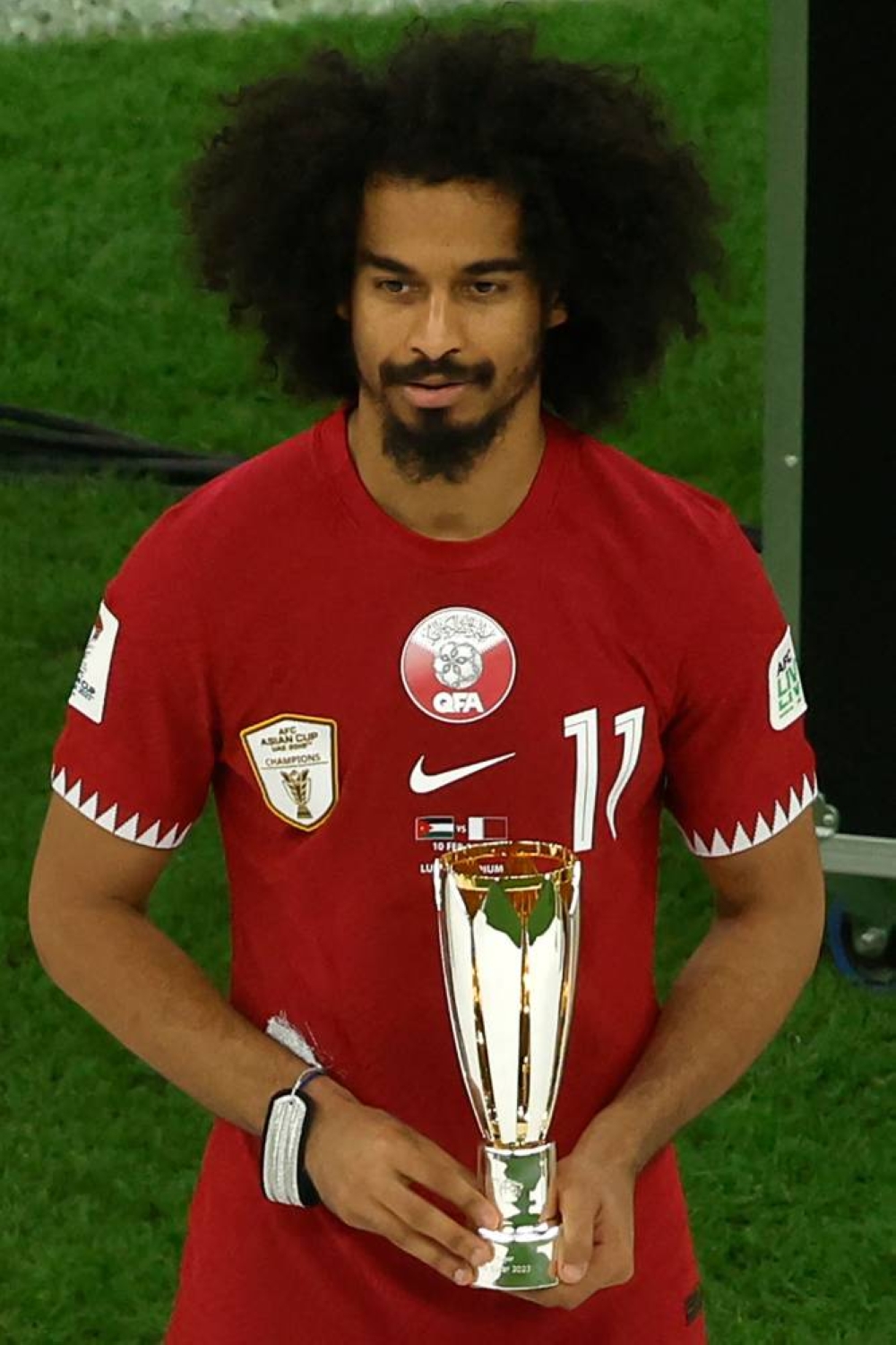 Qatar's forward #11 Akram Afif celebrates with the Most Valuable Player Award trophy during the podium ceremony after the AFC Qatar 2023 Asian Cup final football match between Jordan and Qatar at the Lusail Stadium.
