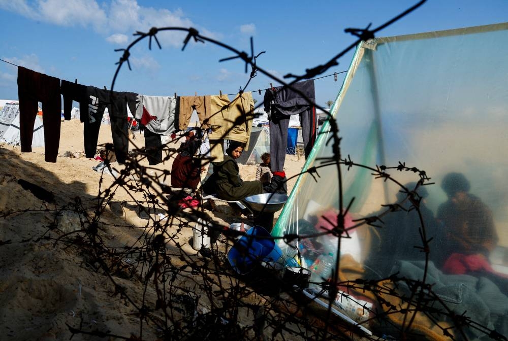 Displaced members of Palestinian Abu Mustafa family, who fled their house due to Israeli strikes, shelter at the border with Egypt, in Rafah on Sunday 