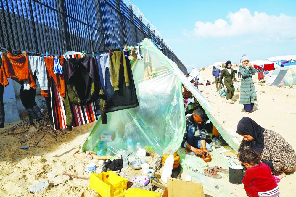
Displaced members of Palestinian Abu Mustafa family, who fled their house due to Israeli strikes, prepare food as they shelter at the border with Egypt, in Rafah in the southern Gaza Strip. 