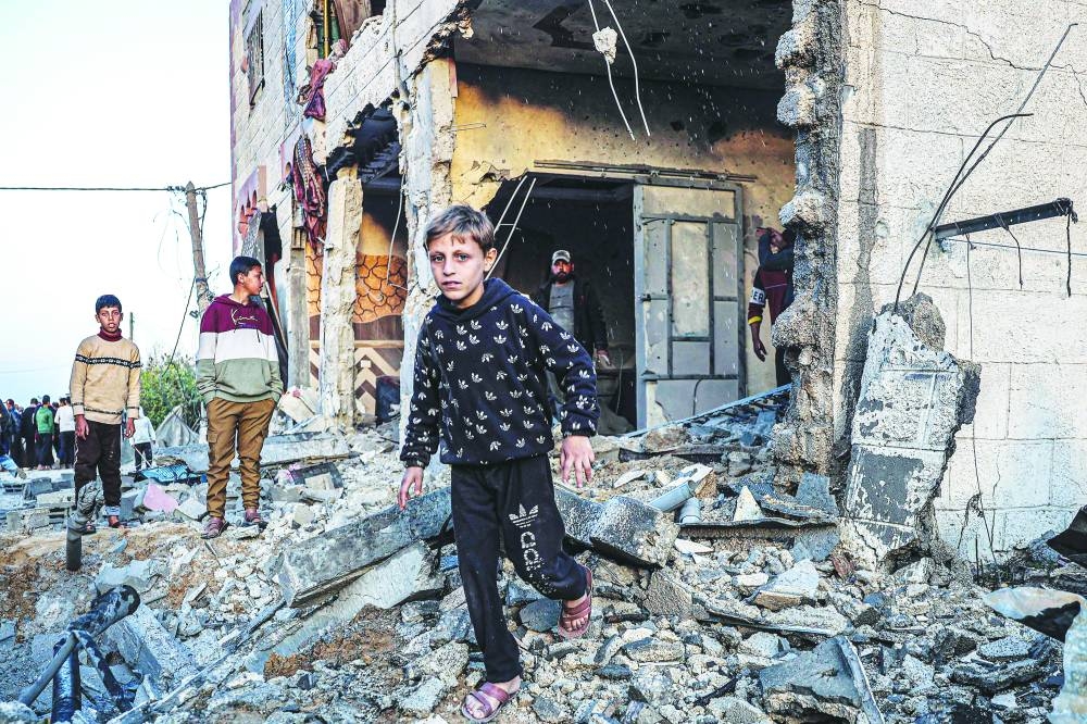 
People walk through the rubble of a building heavily damaged by Israeli bombardment, in Rafah in the southern Gaza Strip, yesterday. 