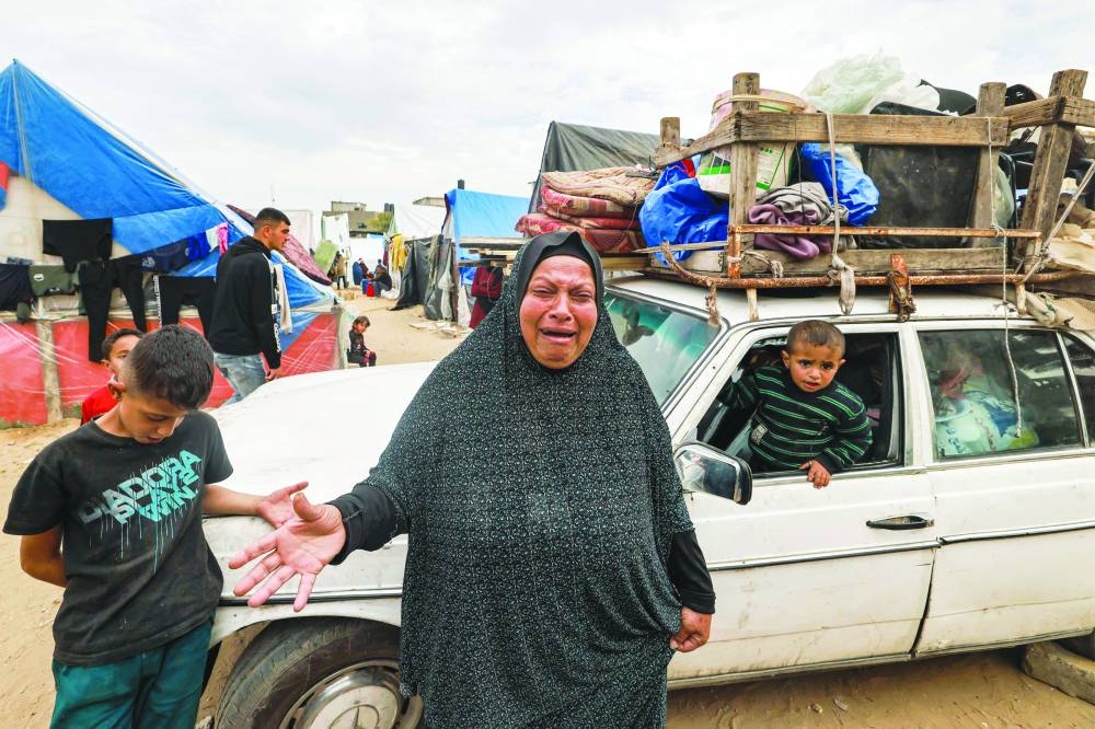 
A woman reacts as she stands before a vehicle loaded with items secured by rope as people flee from Rafah in the southern Gaza Strip, yesterday, north towards the centre of the Palestinian territory amid the ongoing conflict. 