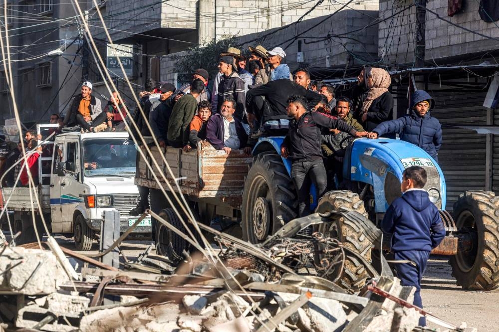 People ride in a cart pulled by a tractor past the rubble of a destroyed building and a mosque minaret in Rafah in the southern Gaza Strip, on Wednesday. AFP