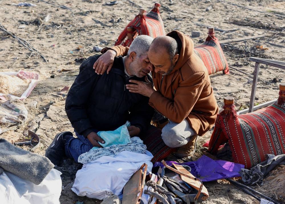 Palestinians react as they gather at the site of an Israeli strike on a house in Rafah, in the southern Gaza Strip, on Sunday. REUTERS