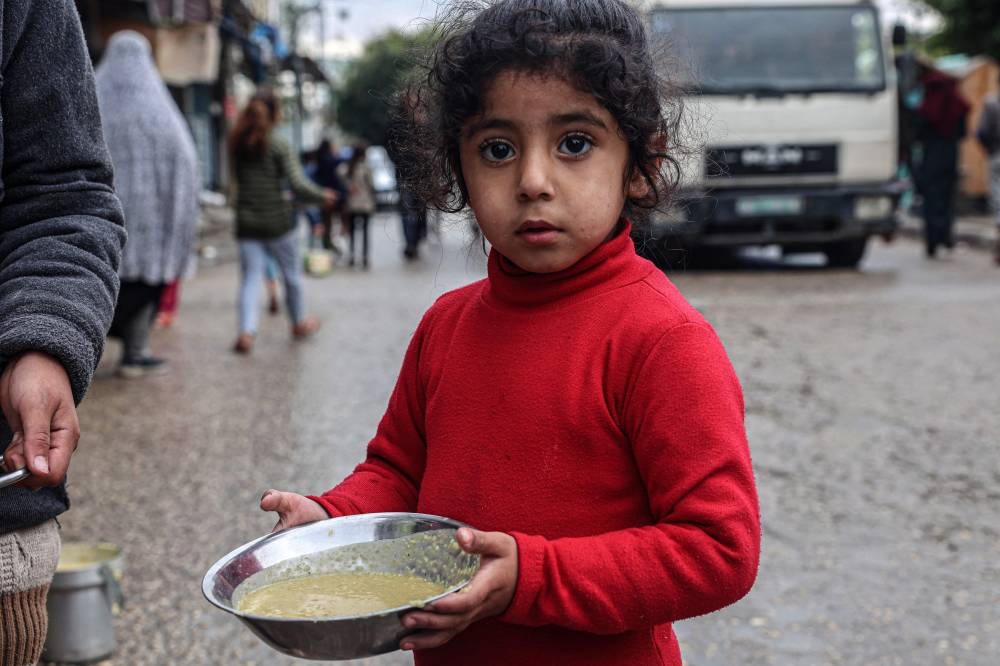 A displaced Palestinian child carries a ration of red lentil soup, distributed by volunteers in Rafah in the southern Gaza Strip on Sunday. AFP