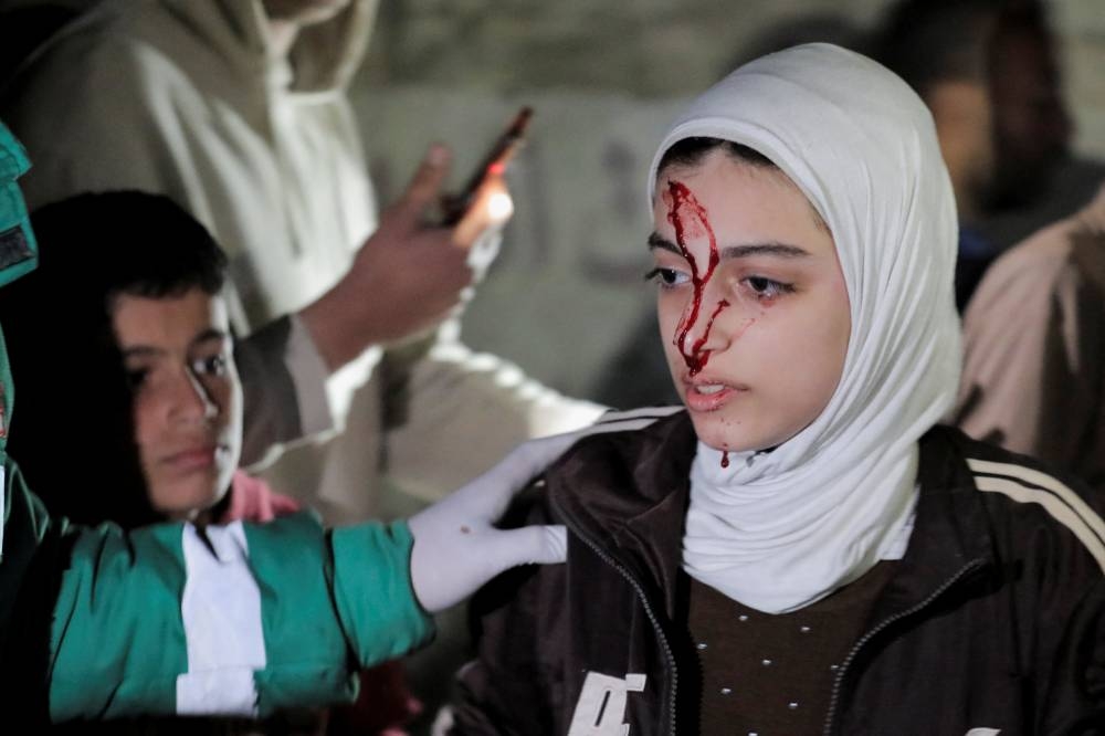 A wounded Palestinian is assisted at the site of an Israeli strike in Deir al-Balah, in the central Gaza Strip Monday. REUTERS
