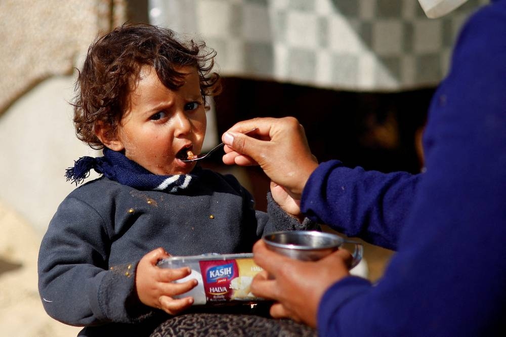 A displaced Palestinian child, who fled due to Israeli strikes, eats in Rafah in the southern Gaza Strip, on Tuesday. REUTERS