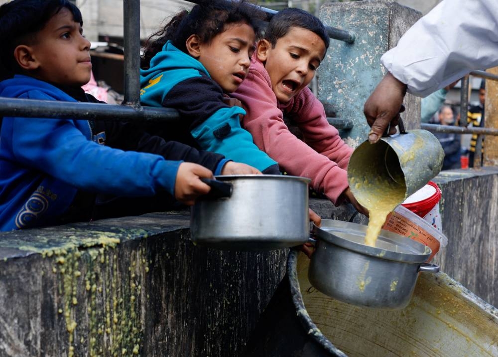 Palestinian children react as they receive food cooked by a charity kitchen amid shortages of food supplies in Rafah, in the southern Gaza Strip, on Tuesday. REUTERS