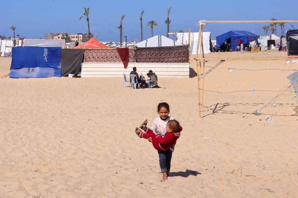 A displaced Palestinian girl holds her brother at a tent camp where they shelter in Rafah on Wednesday. REUTERS