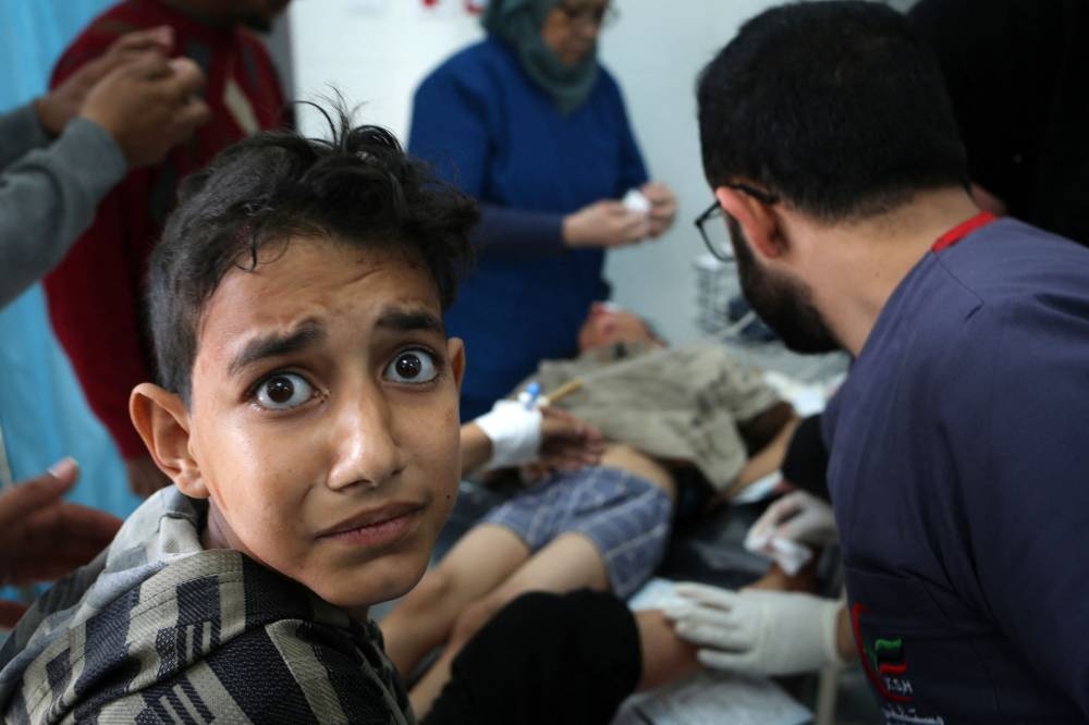 A young boy reacts as a child receives medical attention at the Kuwaiti hospital for wounds sustained in an Israeli bombardment that hit a camp sheltering displaced Palestinians near the Emirati hospital, in Rafah in the southern Gaza Strip on Saturday. AFP