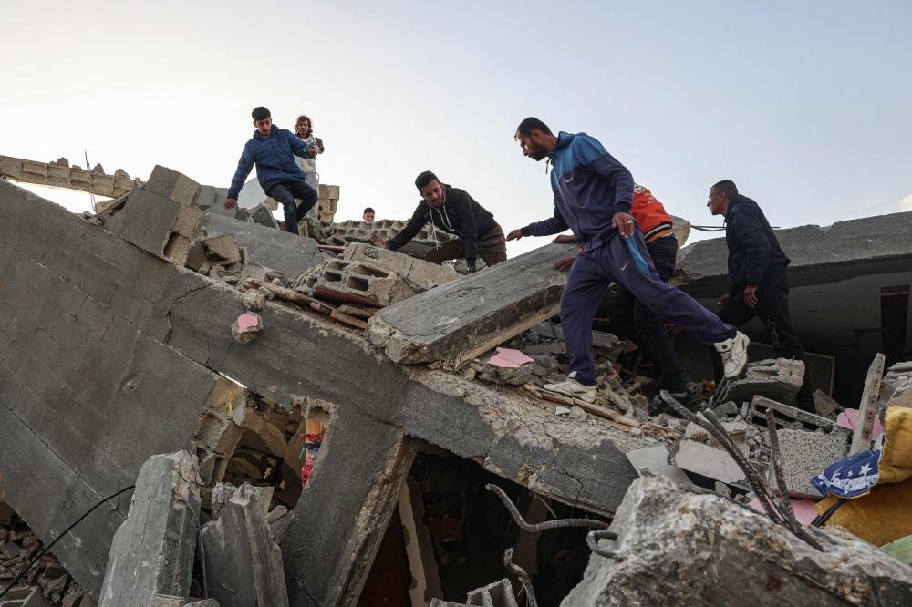 Palestinian men search for salvageable items amid the rubble of a house destroyed in an overnight Israeli air strike in Rafah in the southern Gaza Strip on Sunday. AFP