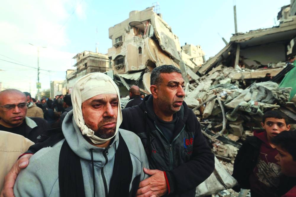 Wounded Palestinian Nidal al-Gharib, who lost his wife and daughter, walks past his neighbours' house destroyed by Israeli bombing in Rafah Monday.