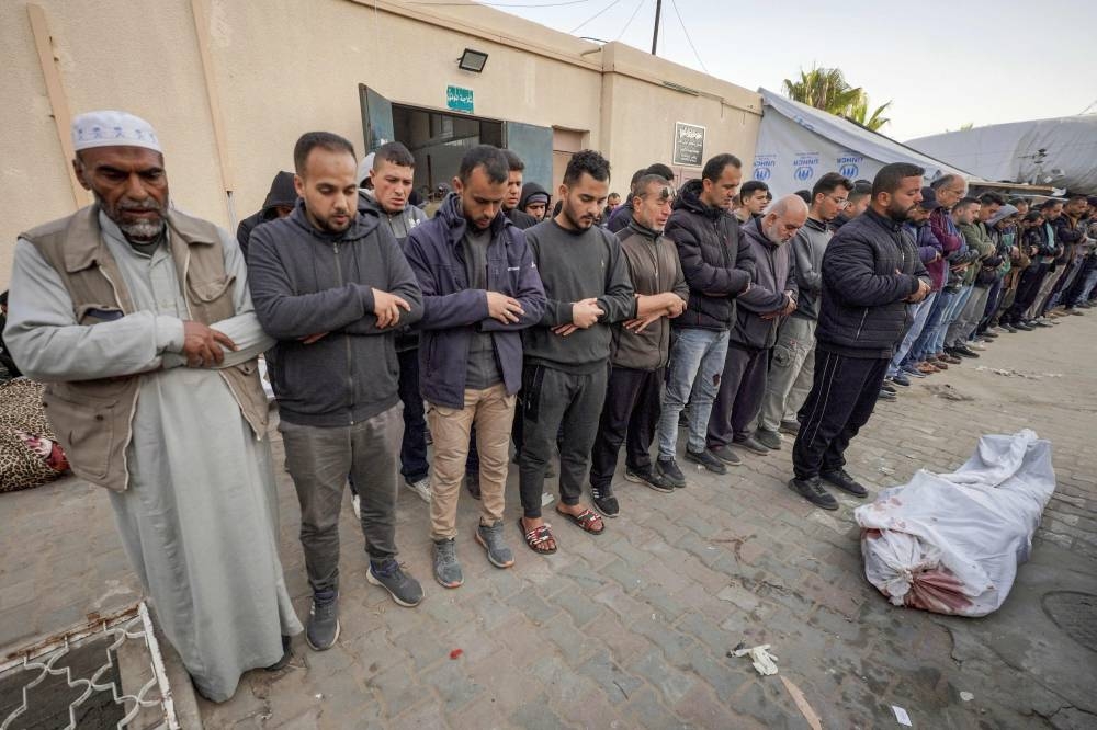 Palestinians pray at al-Aqsa hospital in Deir el-Balah as they mourn over the bodies of loved ones killed during Israeli bombardment, in the central Gaza Strip on Wednesday. AFP