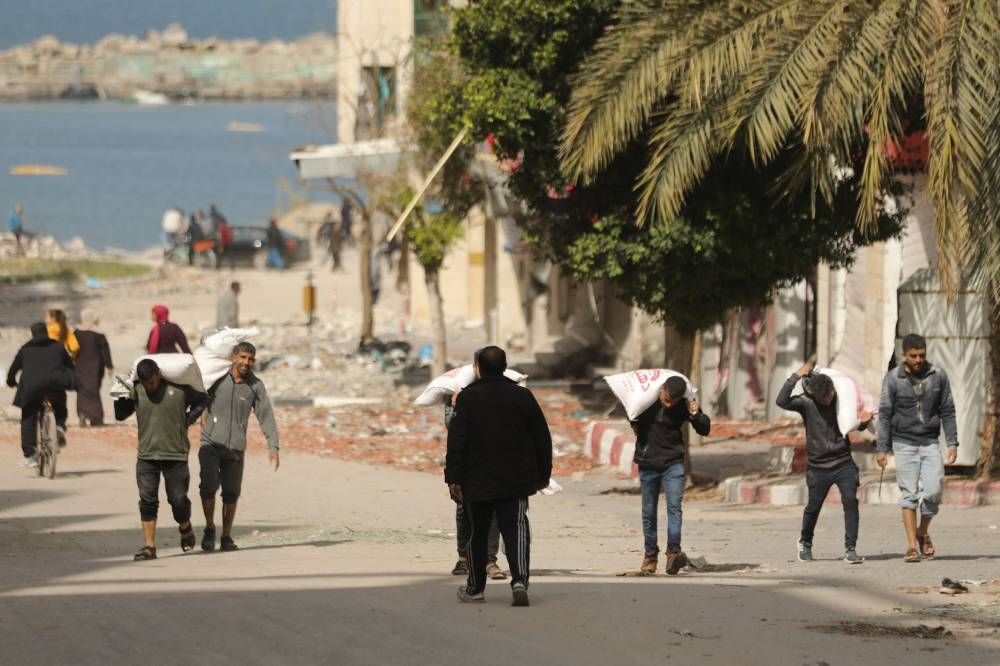 Palestinians transport bags of flour as humanitarian aid arrives in Gaza City on Wednesday. AFP