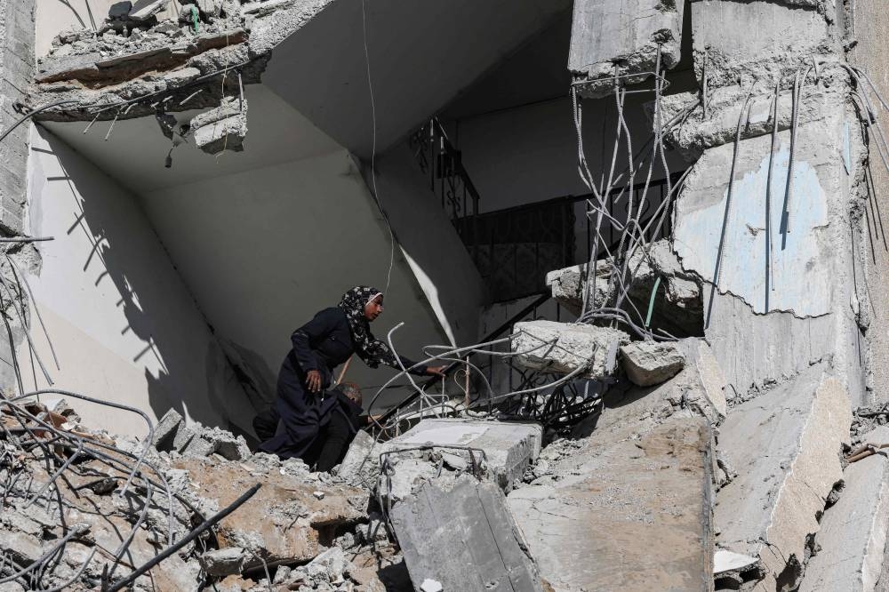 A Palestinian woman searches amid the rubble of a residential building hit in an overnight Israeli air strike in Rafah in the southern Gaza Strip on Saturday. AFP