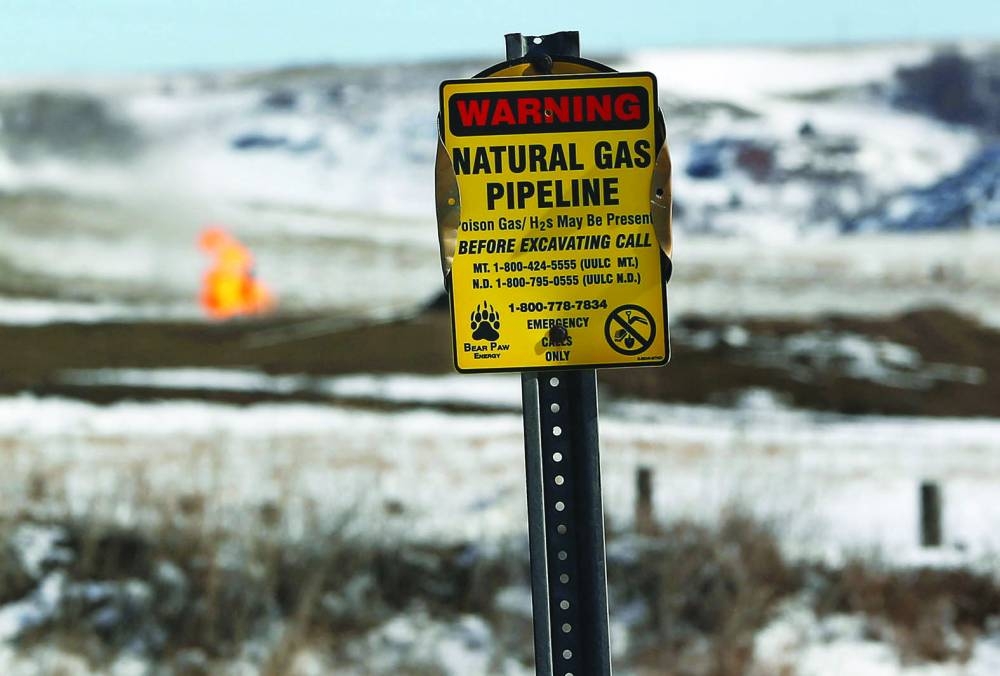 A warning sign for a natural gas pipeline is seen in front of natural gas flares at an oil pump site outside of Williston, North Dakota.  (Reuters)