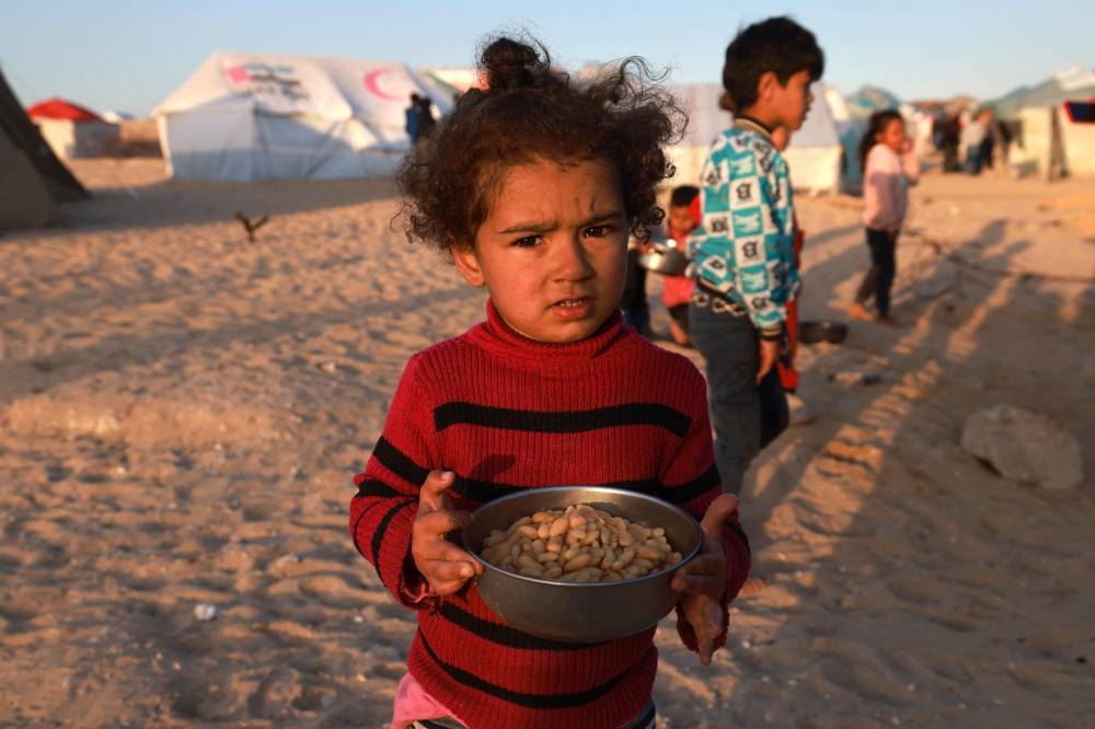 A Palestinian girl holds a bowl of beans before an iftar meal, the breaking of fast, on the first day of the Muslim holy fasting month of Ramadan, at a camp for displaced people in Rafah in the southern Gaza Strip on Monday. AFP