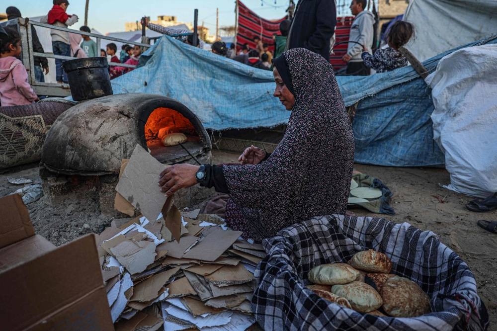 A displaced Palestinian woman bakes bread before an Iftar meal, the breaking of fast, on the first day of the Muslim holy fasting month of Ramadan, in Rafah in the southern Gaza Strip, on Monday. AFP