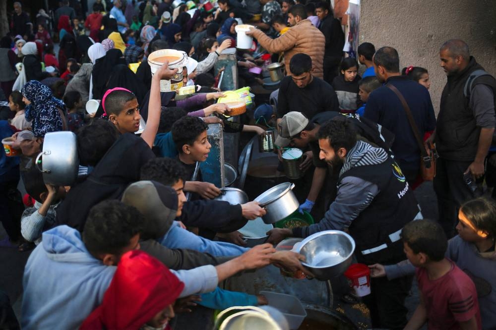 Displaced Palestinians collect food donated by a charity before an Iftar meal, the breaking of the fast, on the first day of the Muslim holy fasting month of Ramadan in Rafah, on Monday. AFP