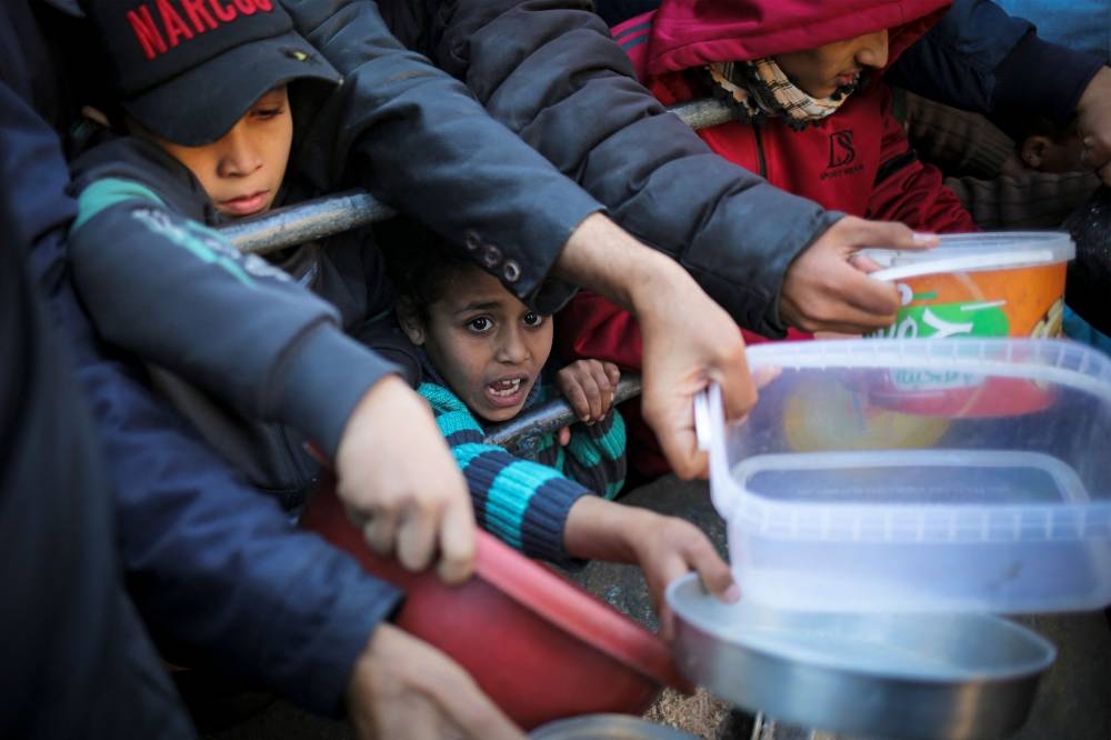Displaced Palestinians collect food donated by a charity before an Iftar meal, the breaking of the fast, on the first day of the Muslim holy fasting month of Ramadan in Rafah, on the southern Gaza Strip on Monday. AFP