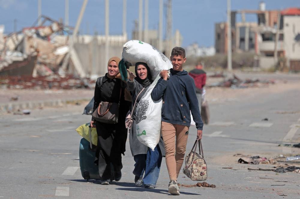 Displaced Palestinians walk along a road near the rubble of houses destroyed by Israeli bombardment at the Nuseirat area in the central Gaza Strip on Friday. AFP