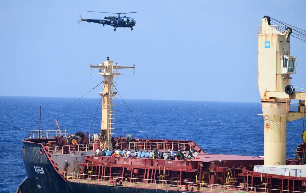 People on board of the recaptured Maltese ship the MV Ruen, as an Indian Naval helicopter flies overhead. AFP/ INDIAN NAVY