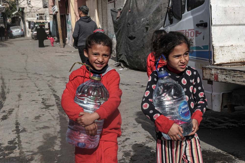 Children carry water in Rafah on the southern Gaza Strip on Sunday. AFP