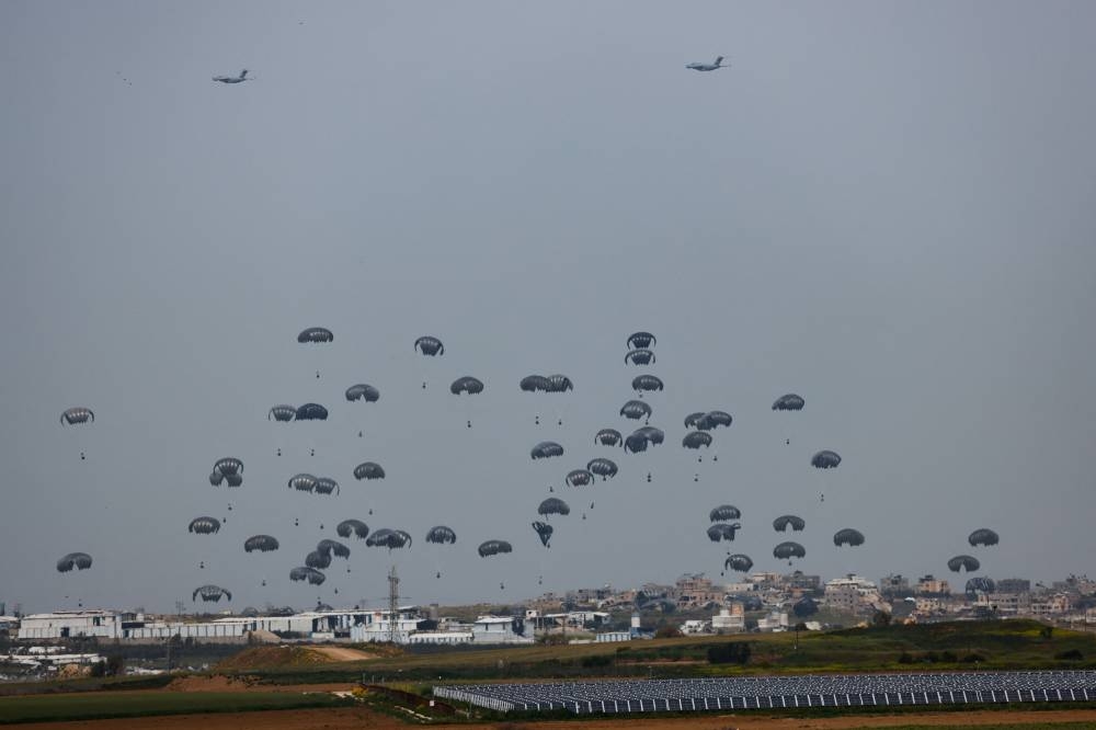 Humanitarian aid falls through the sky towards the Gaza Strip after being dropped from an aircraft as seen from Israel's border with Gaza, in southern Israel, on Sunday. REUTERS