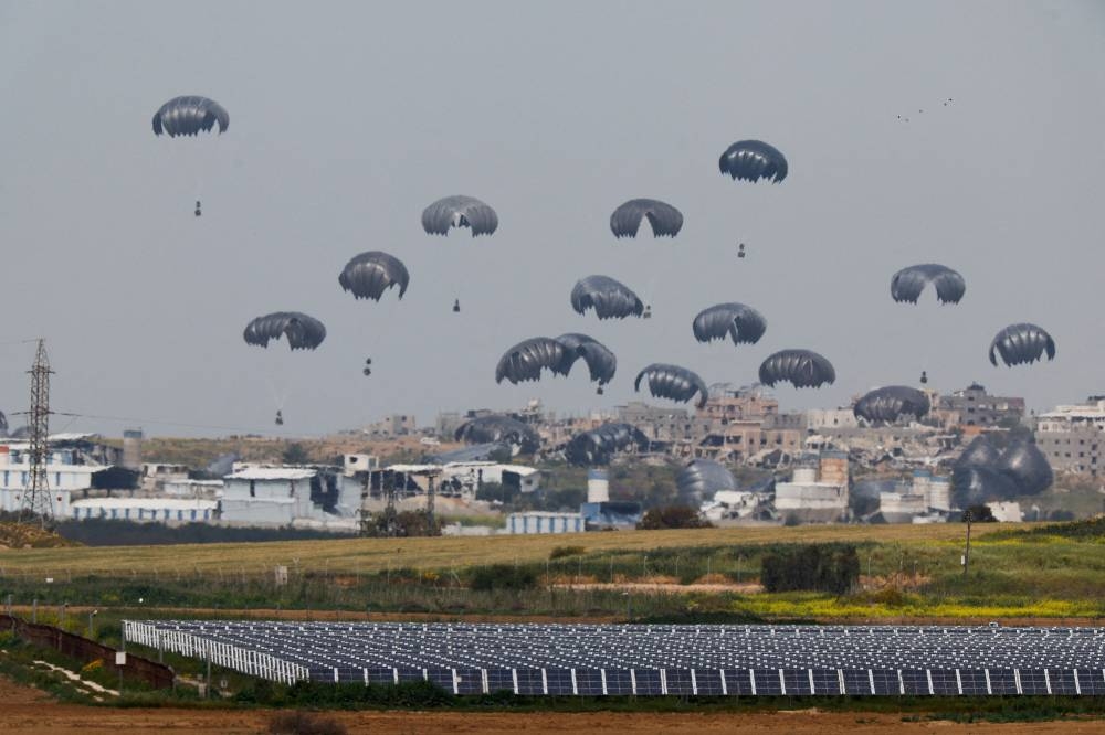 Humanitarian aid falls through the sky towards the Gaza Strip after being dropped from an aircraft, as seen from Israel's border with Gaza, in southern Israel, on Sunday. REUTERS