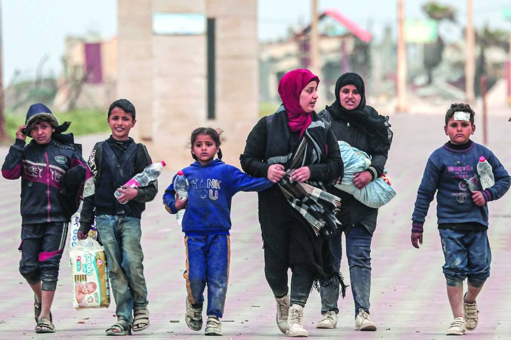 Displaced Palestinians fleeing from the area in the vicinity of Gaza City's al-Shifa hospital walk along the coastal highway as they arrive at the Nuseirat refugee camp in the central Gaza Strip Monday.
