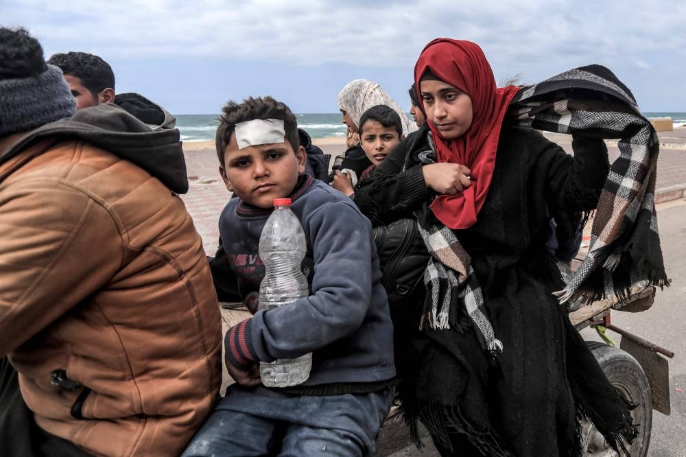 Displaced Palestinians fleeing from the area in the vicinity of Gaza City's al-Shifa hospital ride on a donkey-drawn cart as they arrive at the Nuseirat refugee camp in the central Gaza Strip on Monday. AFP
