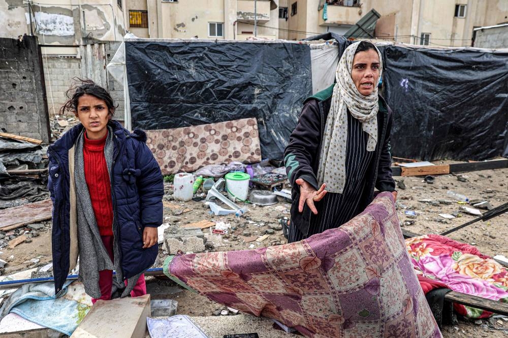 A woman reacts as she holds a mattress while standing before shelters erected outside a damaged building following overnight Israeli bombardment at the Rafah refugee camp in the southern Gaza Strip Tuesday. AFP