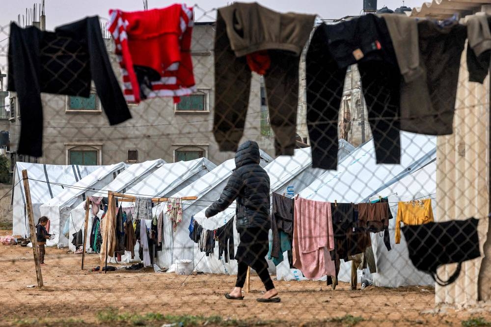 A person walks past drying clothes hanging on a laundry line outside tents housing displaced Palestinians in Rafah in the southern Gaza Strip on Tuesday. AFP