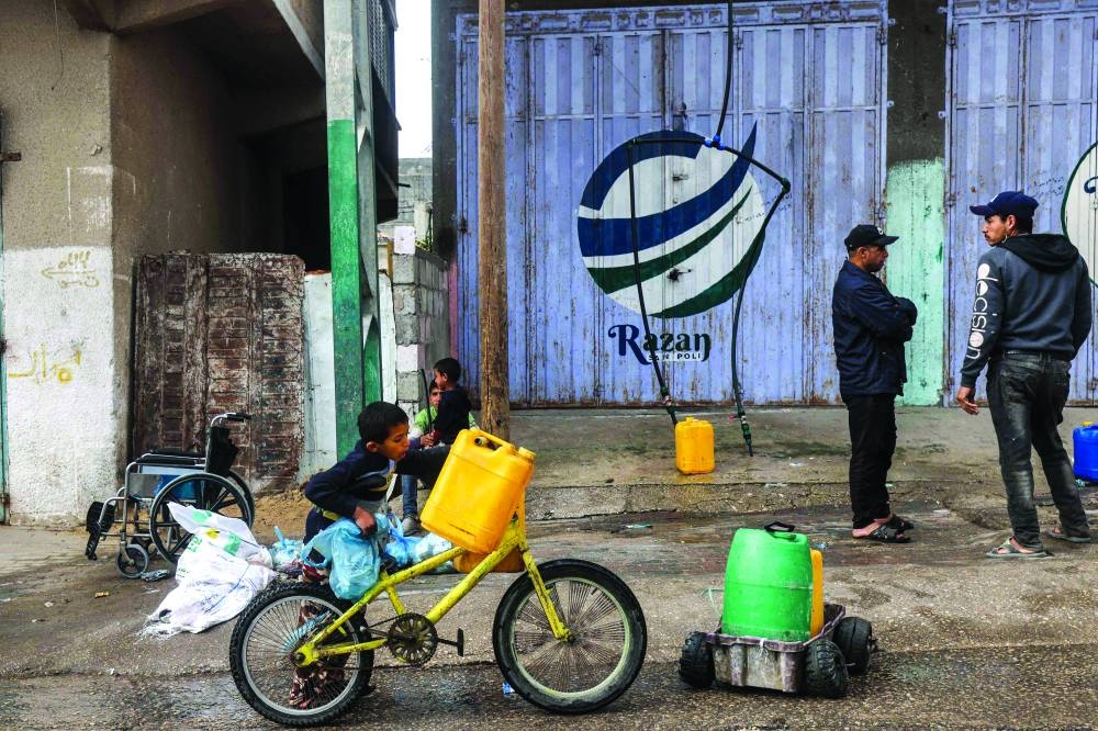 
A boy places a jerrycan on the handlebar of a bicycle in Rafah in the southern Gaza Strip, yesterday, amid the ongoing conflict. 