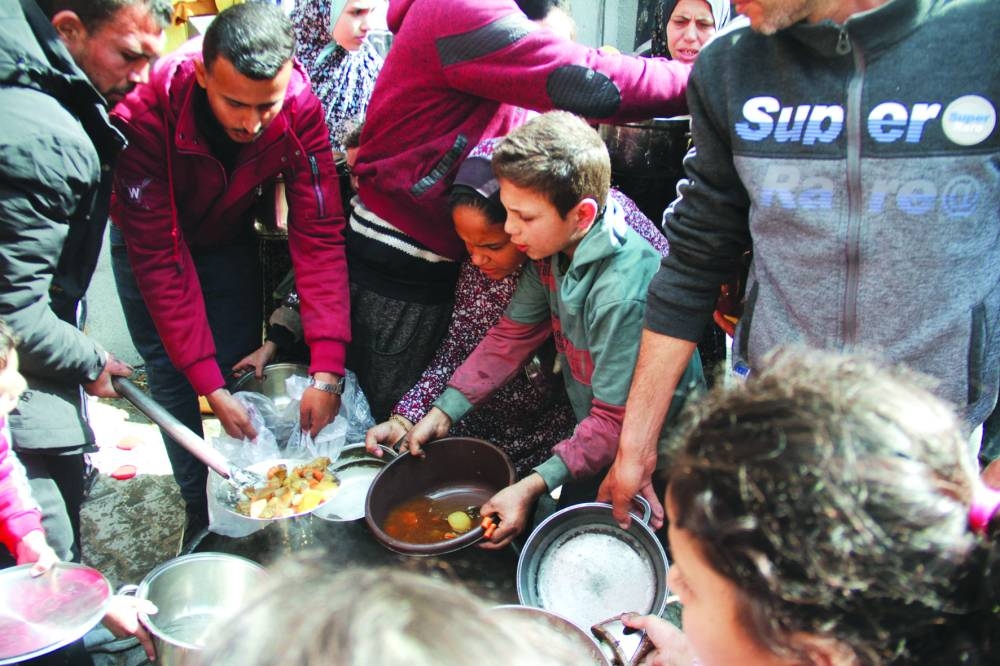
Palestinians gather to receive free food as Gaza residents face crisis levels of hunger, during the holy month of Ramadan, amid the ongoing conflict between Israel and Hamas, in Jabalia in the northern Gaza Strip, yesterday. 