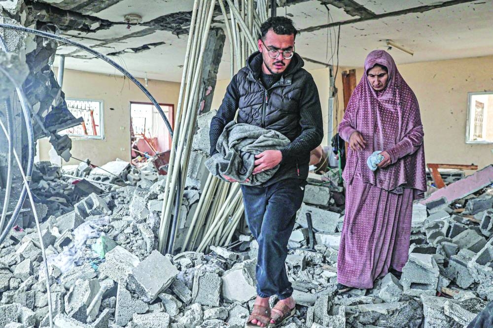 
People inspect the rubble and debris of a building that was hit by overnight Israeli bombardment in Rafah in the southern Gaza Strip, yesterday. 