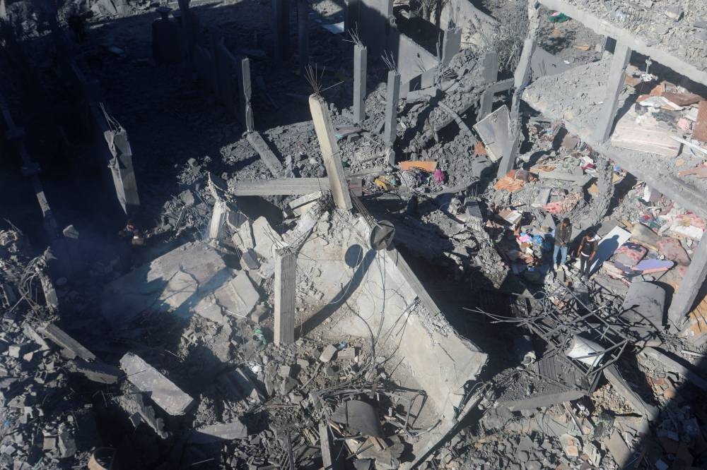 Palestinians inspect the site of an Israeli strike on a residential building at Nuseirat refugee camp in central Gaza Strip, Wednesday. REUTERS