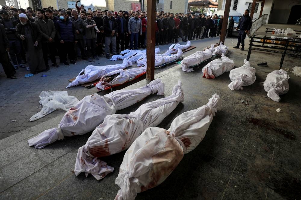 Mourners gather to pray next to the bodies of Palestinian men from an array of clans and factions, who secure aid convoys in Gaza, after they were killed in an Israeli strike, in Gaza City, Wednesday. REUTERS