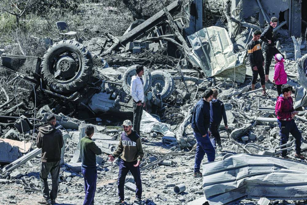 
People inspect the rubble and debris of a building that collapsed following an Israeli air strike in the Rafah refugee camp in the southern Gaza Strip, yesterday. 