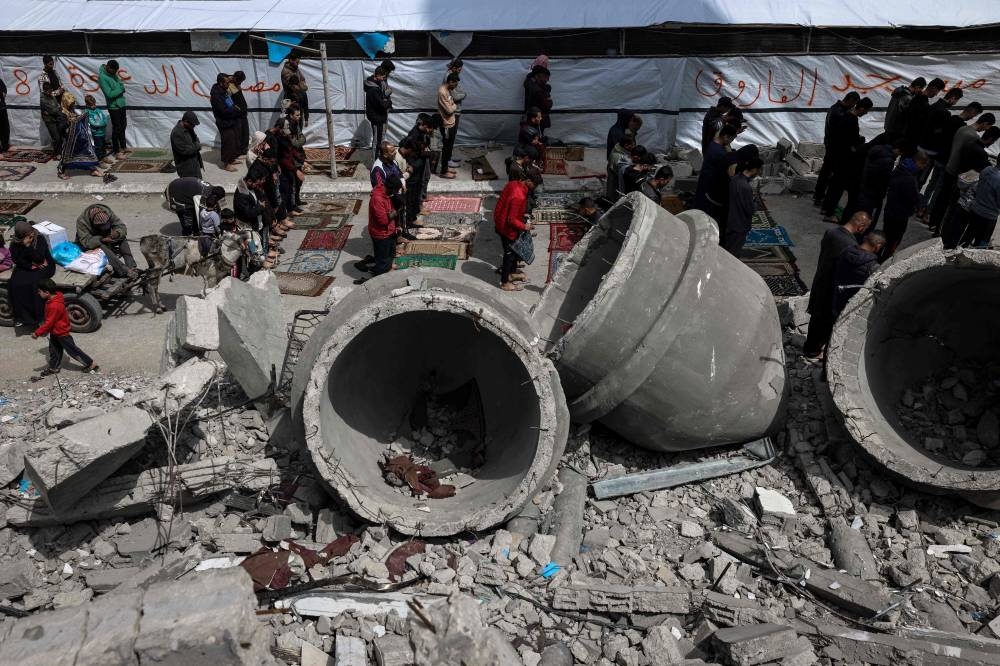 Palestinians perform the Friday noon prayers amidst the ruins of the Al-Faruq Mosque that was destroyed during Israeli bombardment, in Rafah on the southern Gaza Strip, during the Muslim holy fasting month of Ramadan on Friday. AFP